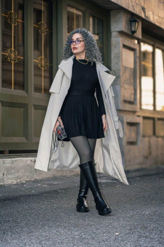 Kvinna i beige trenchcoat och svart klänning på gatan