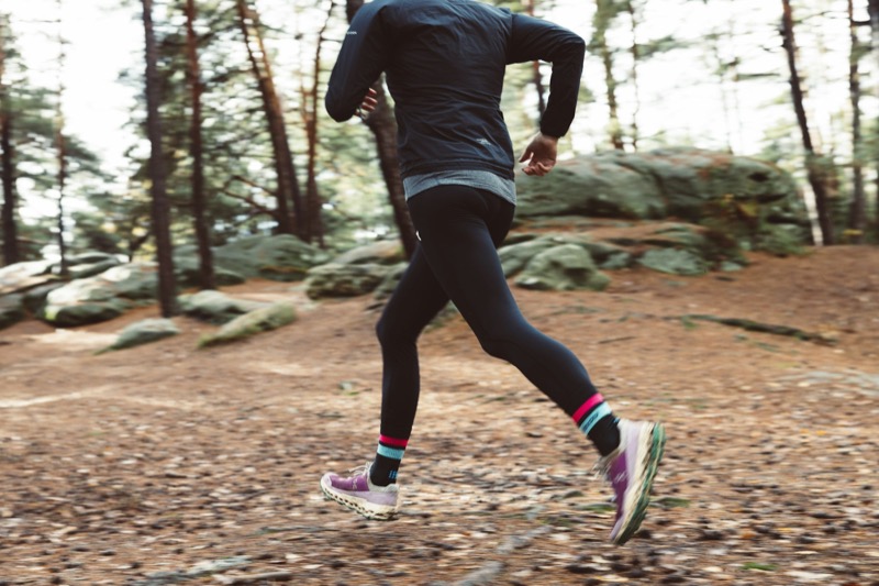 Löpare bakifrån i svarta tights på en skogsstig