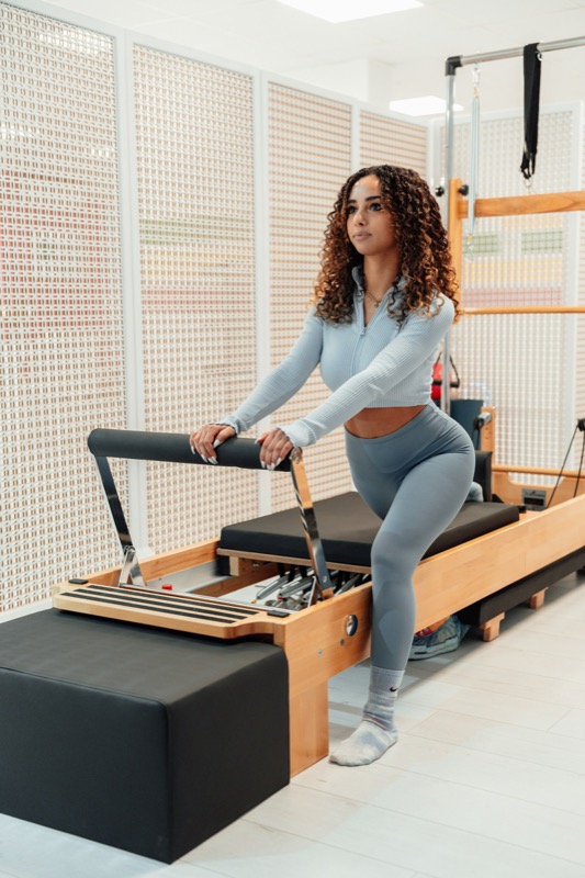 Kvinna i grått träningsset på en pilatesmaskin